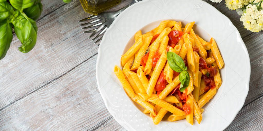 Penne pasta with fresh tomatoes and basil on table