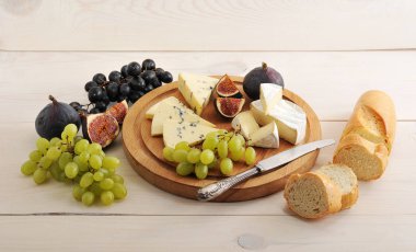 cheese plate - various types of cheeses and figs and grapes on a clipart