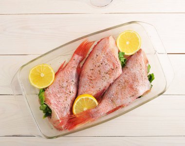 raw sea bass stuffed with parsley and lemon in a glass dish on w clipart