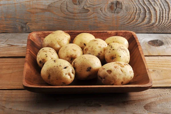 Batatas novas cruas na pele em chapa de madeira — Fotografia de Stock