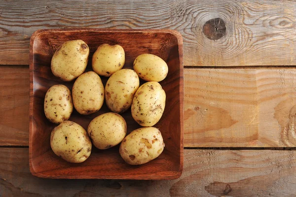 Batatas novas cruas na pele em fundo de madeira rústica — Fotografia de Stock