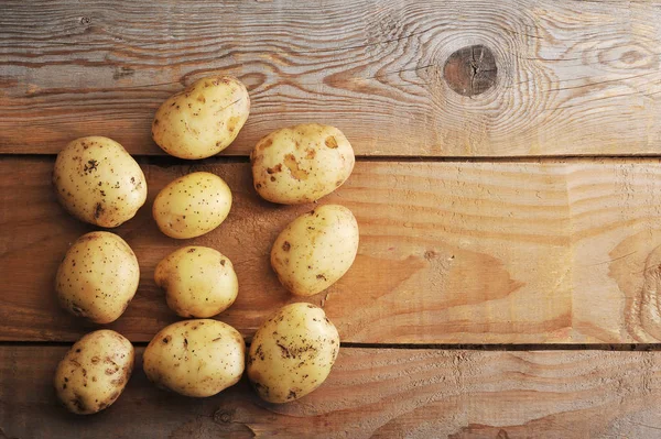 Batatas novas cruas na pele em fundo de madeira rústica — Fotografia de Stock