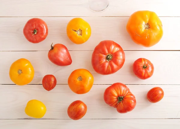 Rode en gele tomaten op houten witte achtergrond — Stockfoto