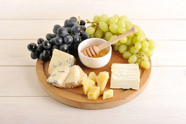 Prato de queijo - vários tipos de queijo, uvas verdes e pretas , — Fotografia de Stock