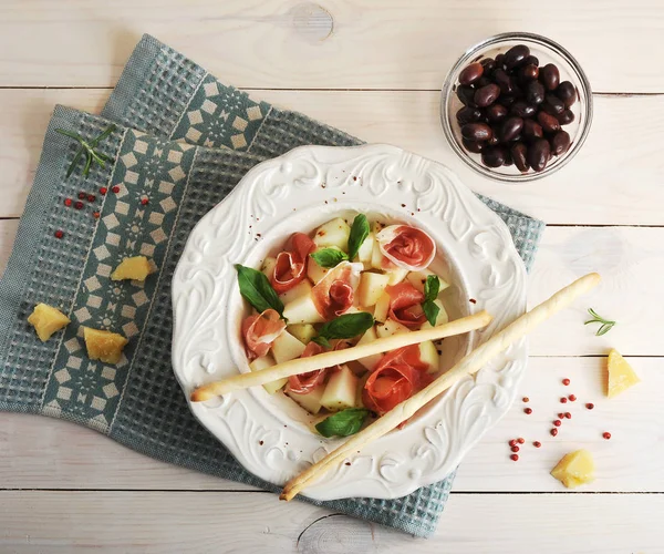 Ham met meloen en breadsticks op een plaat, olijven en parmezaan c — Stockfoto