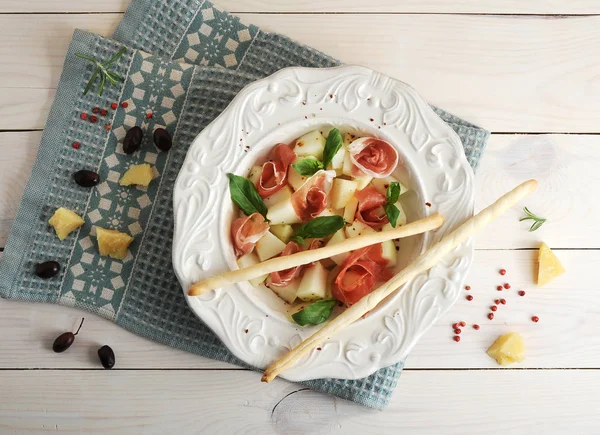 Ham met meloen en breadsticks op een plaat, olijven en parmezaan c — Stockfoto