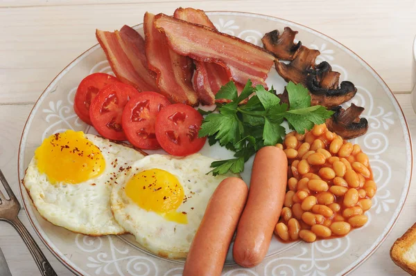 Ovos fritos com bacon, tomate, feijão, cogumelos e salsichas — Fotografia de Stock