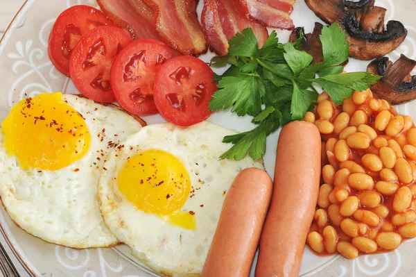 Sázené vejce se slaninou, rajčata, fazole, houby a klobásy — Stock fotografie