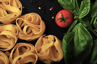 makarna yuva closeup domates ve fesleğen ile siyah arka plan üzerine