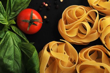 makarna yuva closeup domates ve fesleğen ile siyah arka plan üzerine