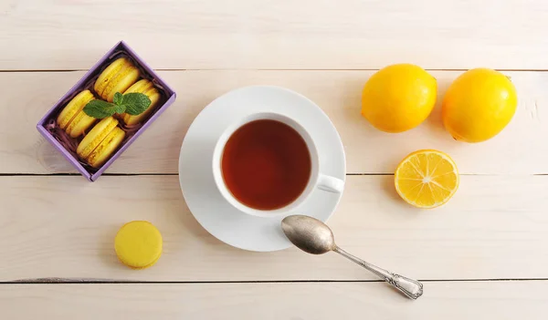 Tea Cup and cake macarons with lemon on wooden background — Stock Photo, Image