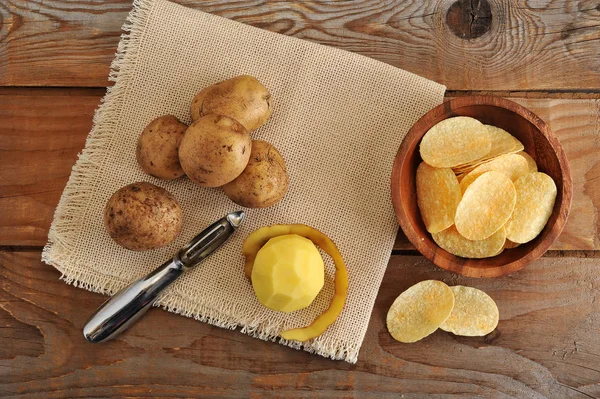 fresh potatoes, potato peeler and potato chips 