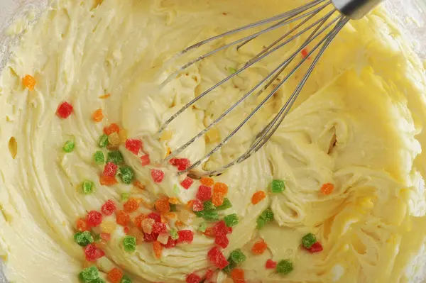 Mixing dough for cake in a bowl with candied fruit — Stock Photo, Image