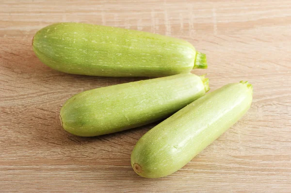 Tre unga gröna zucchini på trä bakgrund — Stockfoto