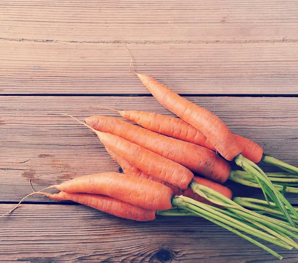 Frescas zanahorias enteras jóvenes sobre fondo rústico de madera — Foto de Stock
