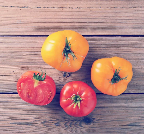 Gele en rode rauwe rijp hele tomaten rustieke houten achtergrond — Stockfoto