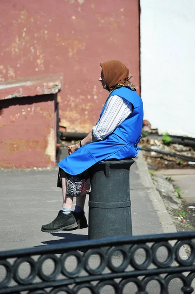 Una donna anziana - vecchio senzatetto seduto nel vecchio logorato — Foto Stock