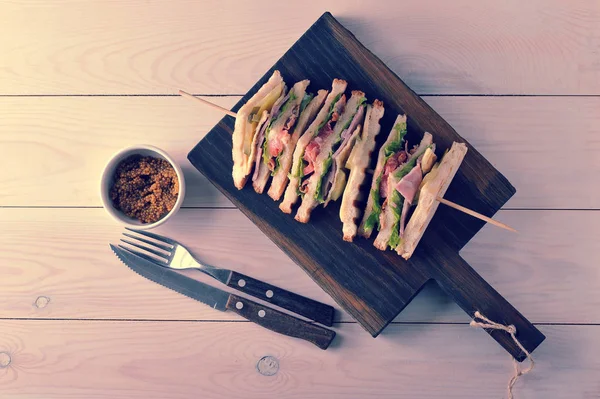 Triangle sandwiches with ham strung on wooden skewers — Stock Photo, Image