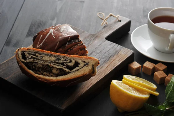 Rollo con semillas de amapola, té, limón y menta sobre fondo de madera — Foto de Stock