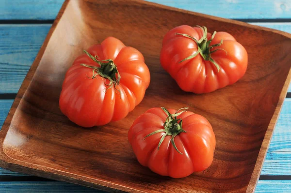 Drie rode rijpe tomaat met groene stengel op een plaat — Stockfoto