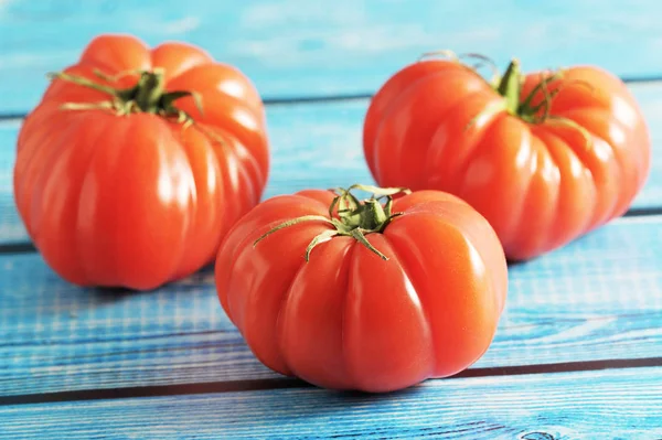 Drie rode rijpe tomaat met groene stengel op een blauwe achtergrond — Stockfoto
