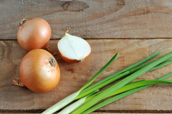 Cebollas enteras, cebolla picada y verde sobre un fondo de madera áspera —  Fotos de Stock