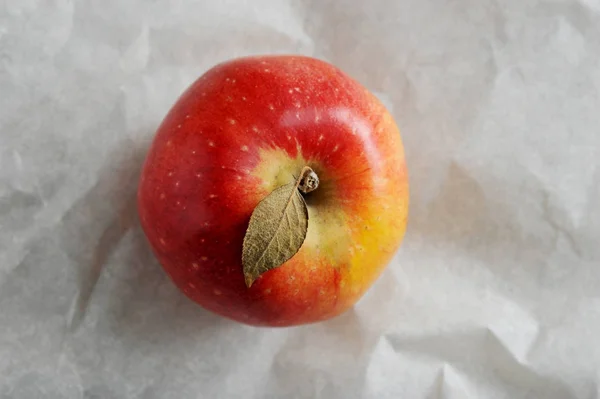 Ένα κίτρινο ώριμο κόκκινο μήλο με φύλλο — Φωτογραφία Αρχείου