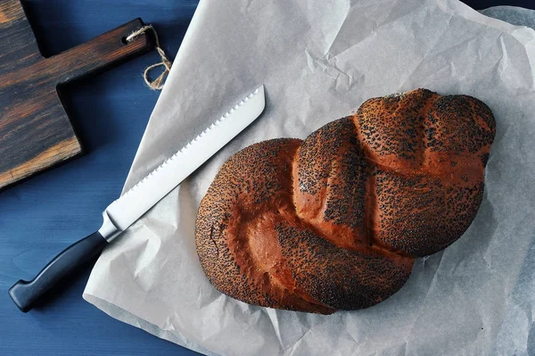 Плетений хліб з маком на коричневому папері з хлібним ножем — стокове фото