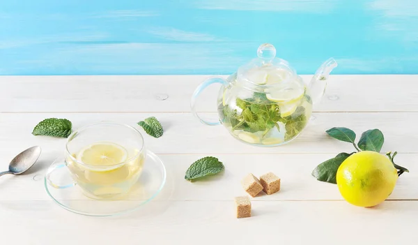Чай с лимоном и мятой в стеклянном контейнере на деревянном фоне — стоковое фото
