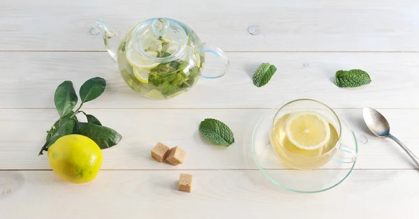 Чай с лимоном и мятой в стеклянном контейнере на белом фоне — стоковое фото