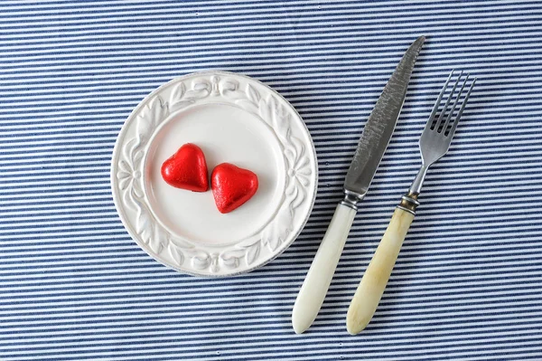 Κόκκινες καρδιές σε ένα πιάτο και ένα μαχαίρι με ένα πιρούνι — Φωτογραφία Αρχείου