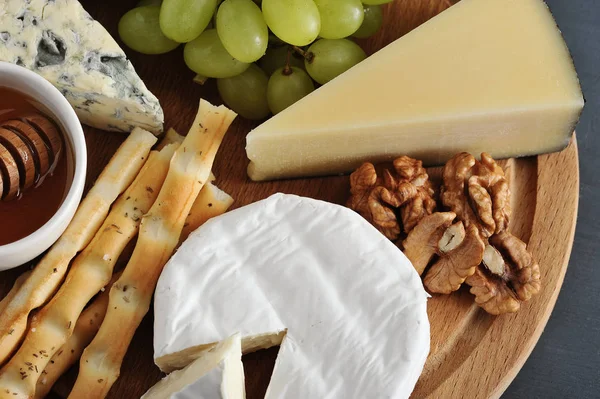 Sobremesa - queijo, paus de pão, mel, nozes e uvas em madeira — Fotografia de Stock