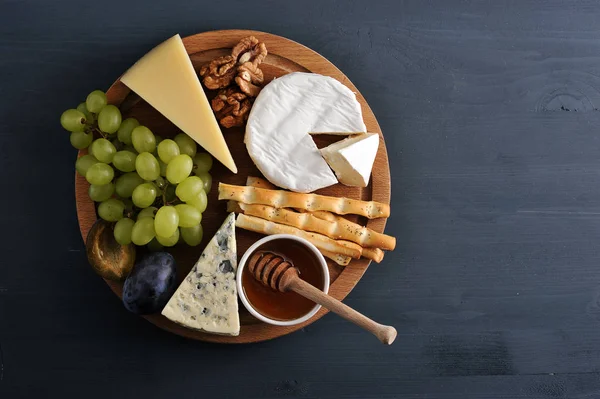Prato de queijo - queijo, uvas, ameixas, nozes, paus de pão e — Fotografia de Stock
