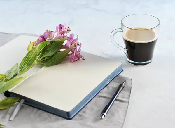 Open notebook with Lily flowers and black coffee — Stock Photo, Image