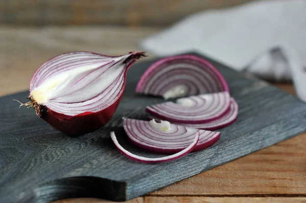 Skär rödlök på en träskiva på en trä rustik bakgrund — Stockfoto