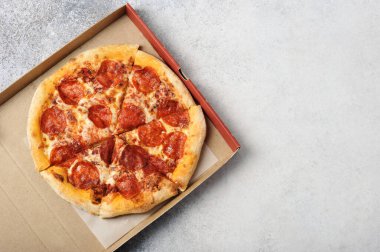 Gri arkaplan manzaralı karton kutuda küçük bir pizza.