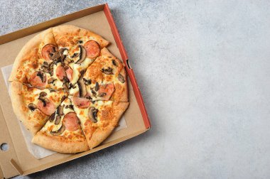 Mantarlı pizza ve gri arka planda jambon. Metin için yer var. Üst görünüm.