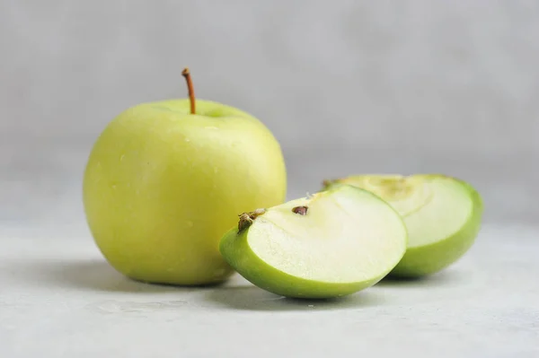 one whole and cut green Apple on a gray background with space for text