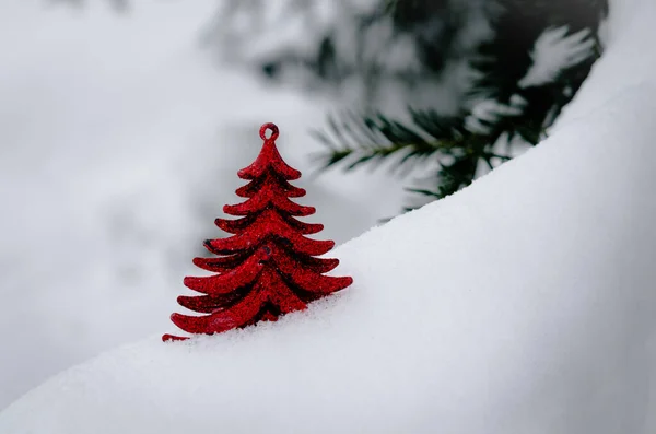 Красное рождественское украшение, висящее на заснеженной сосне снаружи в зимний сезон — стоковое фото