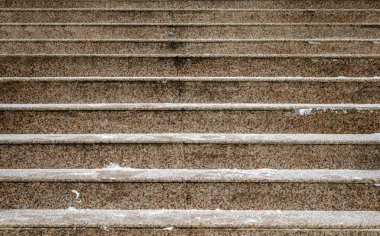 Dışarıdaki paslı mermer merdivenlerin karla kaplı olduğu yakın plan.