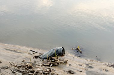 Kırık plastik akordeon hortumu nehir kıyısında terk edilmiş. .