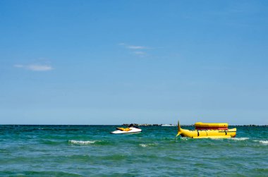 Denizde tatil yaparken rahatlatıcı aktiviteler. Deniz kenarında yüzen sarı muz teknesi eğlence için kullanılmaya hazır. .
