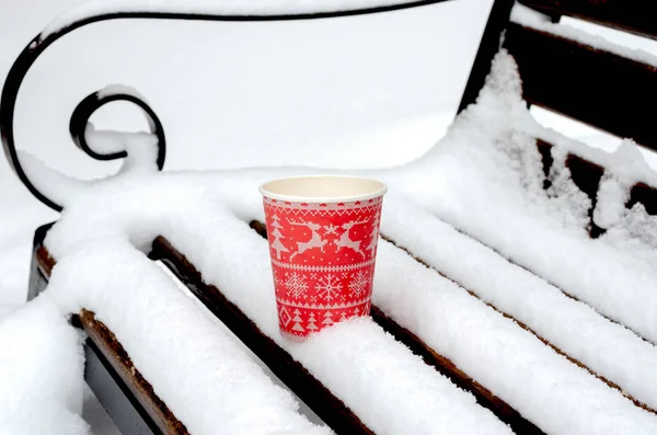 Vue en angle élevé de tasse de café rouge sur un banc recouvert de neige dans le parc — Photo