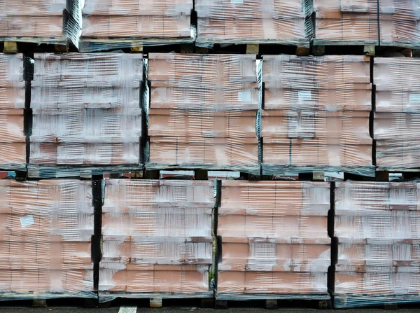 Paquetes de ladrillo embalados en lámina de plástico exterior junto a la tienda de materiales y suministros de construcción  . — Foto de Stock