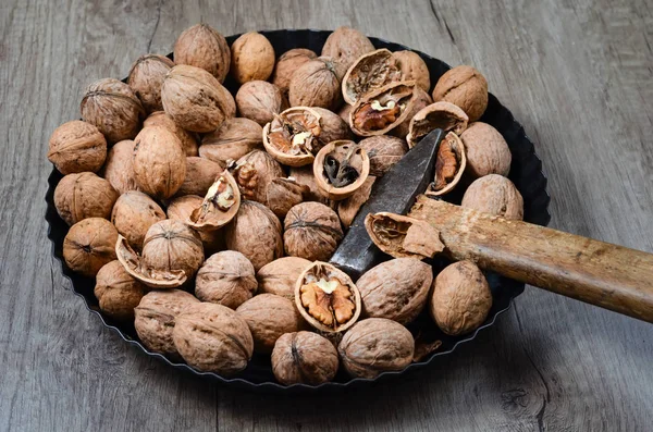 Kırık ceviz ve demir bir tavada bir çekiç, ahşap bir masaya yerleştirilmiş. .