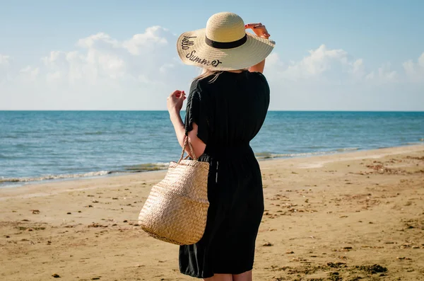 Young   women  with  black dress and   straw hat relaxing on corfu beach at sunset. — Stock Photo, Image