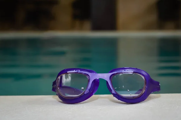 Primer plano de las gafas de baño azules en el borde de una piscina interior  . — Foto de Stock