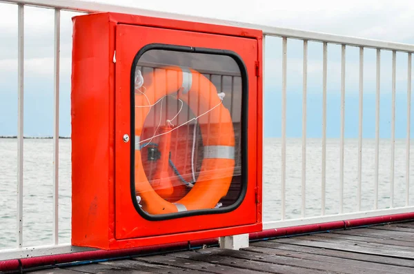 Rettungsboje in der Vitrine, die an einem Brückengeländer am Ufer hängt. Werkzeuge zur Rettung von Menschen im Notfall . — Stockfoto