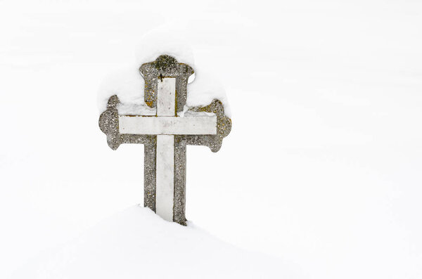 Христианский каменный крест на кладбище, покрытый снегом
 .
