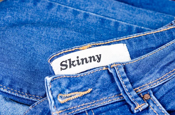 Jeans azuis jovens modernos ganga com tag skinny para pessoas magras. Mulheres e homens acessório de moda. Vista superior, copyspace . — Fotografia de Stock